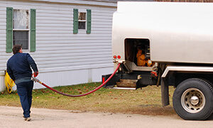 oil delivery man with hose from heating oil tanker